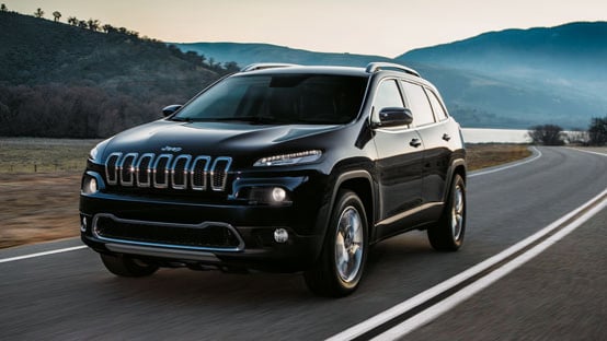 Grey Jeep Cherokee driving along a country road.